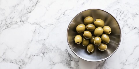 Fresh green olives beautifully arranged in a silver bowl. The bowl rests on a smooth, white marble surface. Perfect for culinary designs and healthy recipes. AI