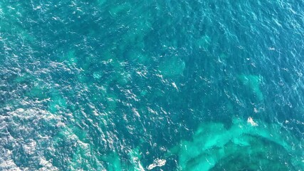 Aerial view of Vibrant blue ocean waters with gentle waves reflecting sunlight during a clear day