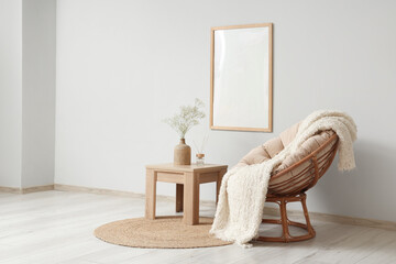 Coffee table with gypsophila flowers in vase and armchair in living room