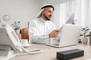Arab businessman working with papers at table in office