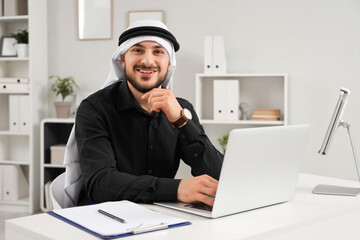 Arab businessman working with laptop at table in office