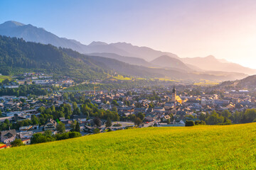 Fototapeta premium Sunrise casts a warm glow over Schladming, highlighting the charming architecture and lush landscapes of this beautiful Austrian town nestled in the Low Tauern mountains.
