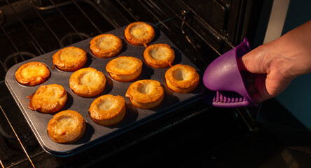 A gloved hand removes a tray of muffins from the oven. The muffins are golden brown, crispy on the outside, and fluffy on the inside. Perfect for restaurant menus, food websites, and food advertising