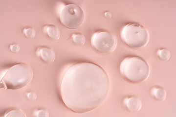 Closeup of translucent gel droplets on a soft pink surface, highlighting the beautiful textures of skincare