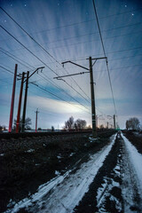 Fototapeta premium Electricity power lines at the night with beautiful night and clear sky with stars , night photography in the station and power lights.Night sky with lights