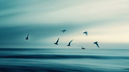 Obraz premium A group of seagulls flying above the ocean on a cloudy day against a blue backdrop