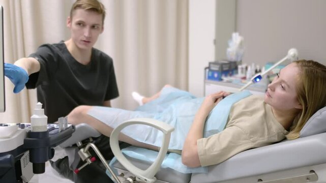 A gynecologist - ultrasound specialist performs an intervaginal ultrasound during a woman's appointment. Doctor shows an image of an early pregnancy on the ultrasound screen. IVF treatment protocols