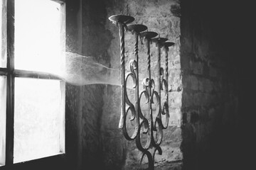 A five-branched candlestick stands beside a window, illuminated by soft light filtering through the glass. Dust motes dance in the ambiance, creating a nostalgic atmosphere.