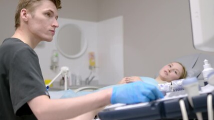 A gynecologist - ultrasound specialist performs an intervaginal ultrasound during a woman's appointment. Doctor shows an image of an early pregnancy on the ultrasound screen. IVF treatment protocols