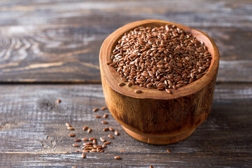 Flax seeds in a rustic wooden bowl on a wooden table with copy space
