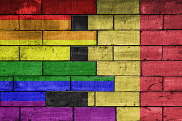colourful painted big flag of belgium and rainbow gay pride flag on a massive old brick wall...