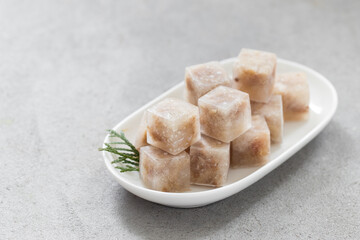 Jellied meat in the shape of a mini cubes. On a plate. Light background. Close up
