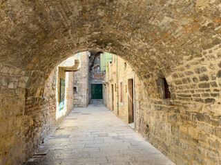 Obraz premium Split, Croatia - July 1, 2024: Historic downtown. Underpass with half circle roof of ancient stones in alley between residential apartments and housing, outside Diocletian Palace.