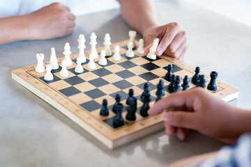 Playing chess games on mini wooden chessboard by moving piece of chess, soft focus, concept for relaxation of people for developing brain skills.