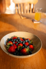 Warm scene of fresh strawberries and blueberries on sunlit wooden table