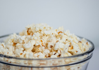 Tasty popcorn in a glass bowl on white table background 