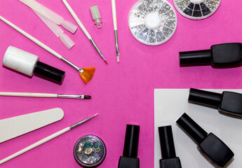 manicure tools on a bright pink background: varnish, brushes, file, glitter, tips