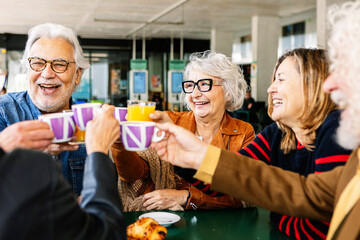Happy group of senior people enjoying coffee at cafeteria bar. Retired generation community having...