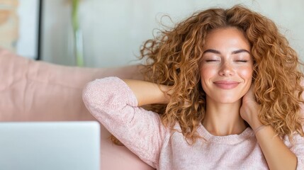 Naklejka premium Happy young woman with curly hair relaxing on a pink sofa at home with her eyes closed.