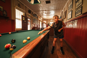 Teenage male playing 8 ball pool on billiard table in Australian pub