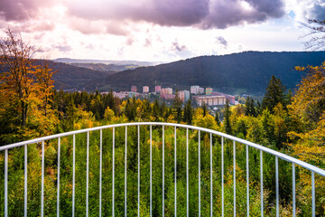 Fototapeta premium View from Spicka lookout tower showcases the vibrant autumn foliage of the Jizera Mountains, revealing a picturesque landscape of Tanvald nestled among the trees.