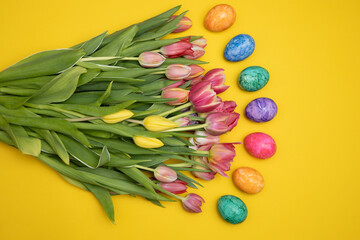 A Beautiful Arrangement of Colorful Tulips and Bright Easter Eggs on a Yellow Background. composition with free space for text