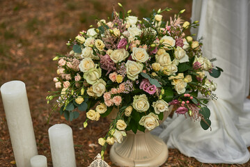 Elegant floral arrangement with white, pink roses, greenery, ivory candles in outdoor setting enhancing wedding decor elegance concept