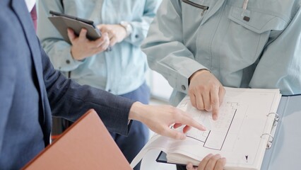 クライアントと打ち合わせをする作業服を着た男性