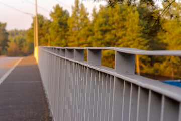 Balustrada (poręcz) na wiadukcie nad torami kolejowymi w lesie. Droga prowadząca przez wiadukt nad torami kolejowymi w lesie w kolorowe jesienne popołudnie. © Grzegorz