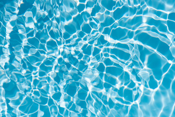 Blue water with ripples on the surface. Defocus blurred transparent blue colored clear calm water surface texture with splashes and bubbles. Water waves with shining pattern texture background.