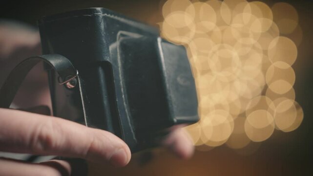 Vintage leather camera case close up with bokeh background, hands examining retro photography equipment