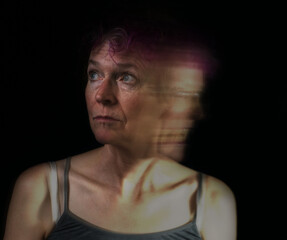 Portrait of an older Caucasian woman. Shows two views of the same person, one calm and composed, and the other violent and disturbed.