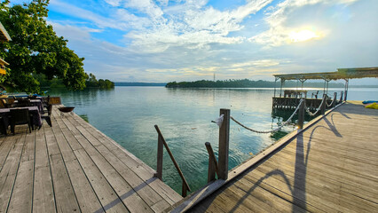 A peaceful waterfront scene with wooden platforms extending over calm waters, surrounded by lush...