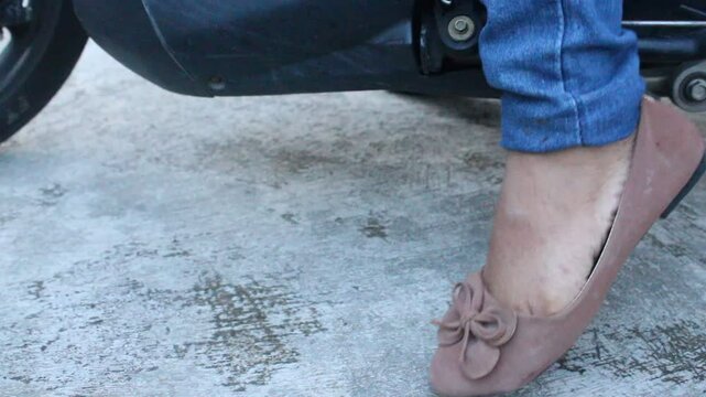 Someone raises the motorbike support. someone is getting ready to ride a motorbike