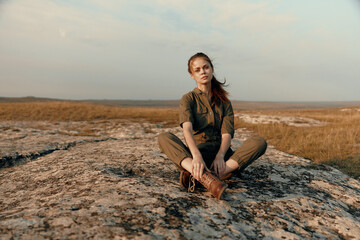 Woman sitting crossedlegged on rock in the middle of field serenity and tranquility in nature