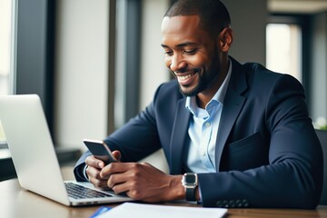 Professional African American Man Engaged in Mobile Communication and Working on Laptop in Modern Office Setting