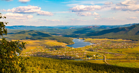 Uzyan village on the bank of the Belaya river against the backdrop of the Ural Mountains of the Kraka ridge on a summer day