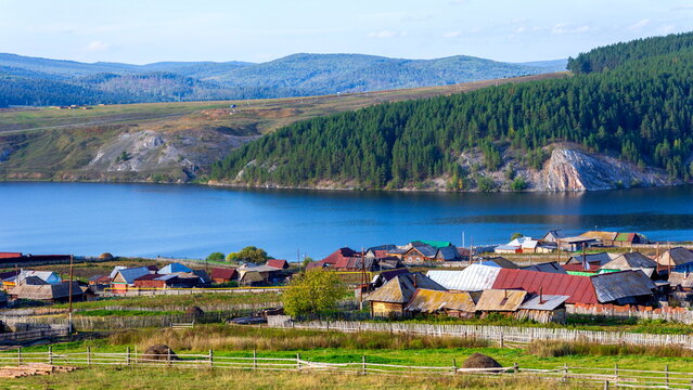 Uzyan village on the bank of the Belaya river against the backdrop of the Ural Mountains of the Kraka ridge on a summer day