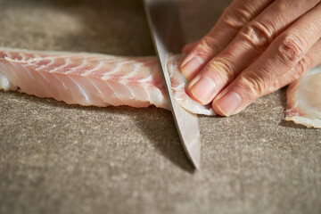 Close-up of hands cutting raw fish with sashimi knife © mnimage