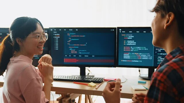 Slow motion back end software developer engineer for computer programming working together on debugging writing computing code, solving complex algorithms display on monitor in office. Burgeoning