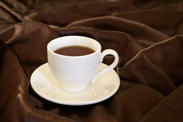 Cup of tea on brown satin background