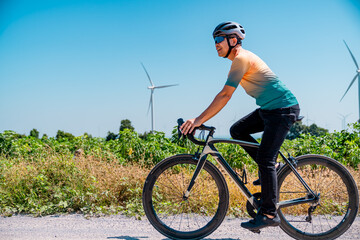 Fototapeta premium Biker enjoying a sunny day on a rural road with wind turbines in the background