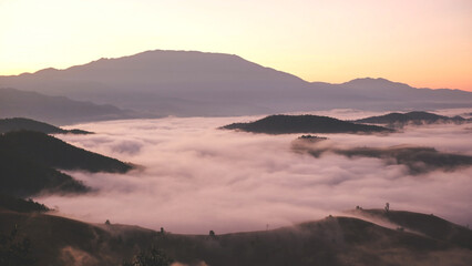 Landscape view of the sea of fog flowing on hills at dawn