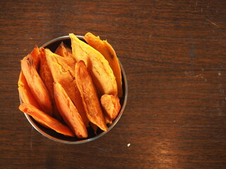top view bowl of baked sweet potato wedges on wooden table