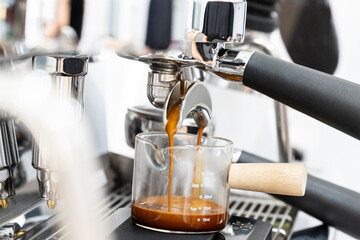 Coffee machine brewing espresso in to glass cup.Barista while preparing and working with coffee machine and making espresso coffee from arabica coffee beans.