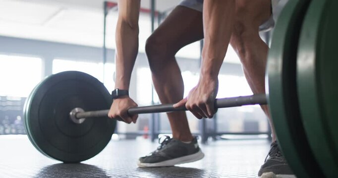 Lifting barbell, man exercising in gym, focusing on strength training