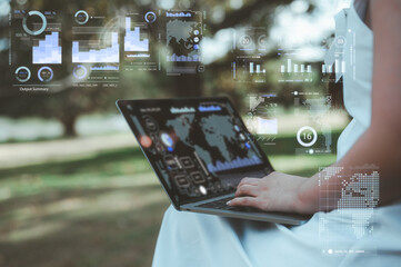 Woman sitting outdoor at park or garden using computer laptop analyse business data charts working...