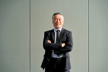 A asian senior businessman wear formal black suit and cross arm  smile face portrait on gray green...