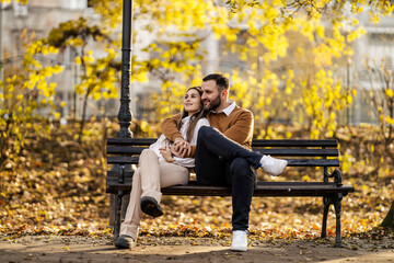 Young happy couple is sitting in city park and hugging.