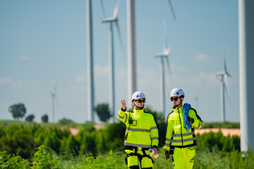 Workers in bright safety gear discuss wind turbine maintenance at a renewable energy site during a...